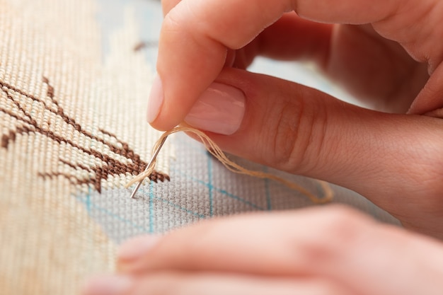 Hands stitching an embroidery pattern